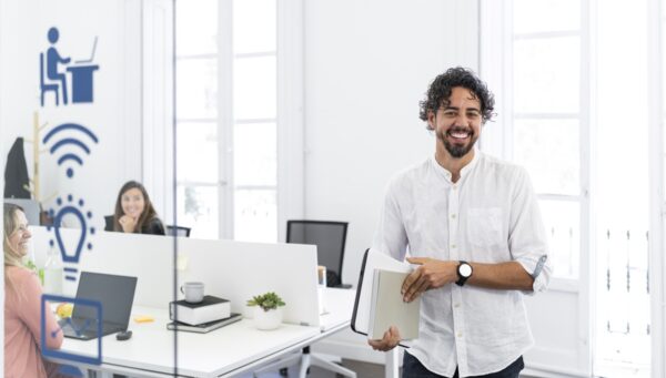 Portrait of a businessman holding documents and smiling in a modern office with his coworkers working